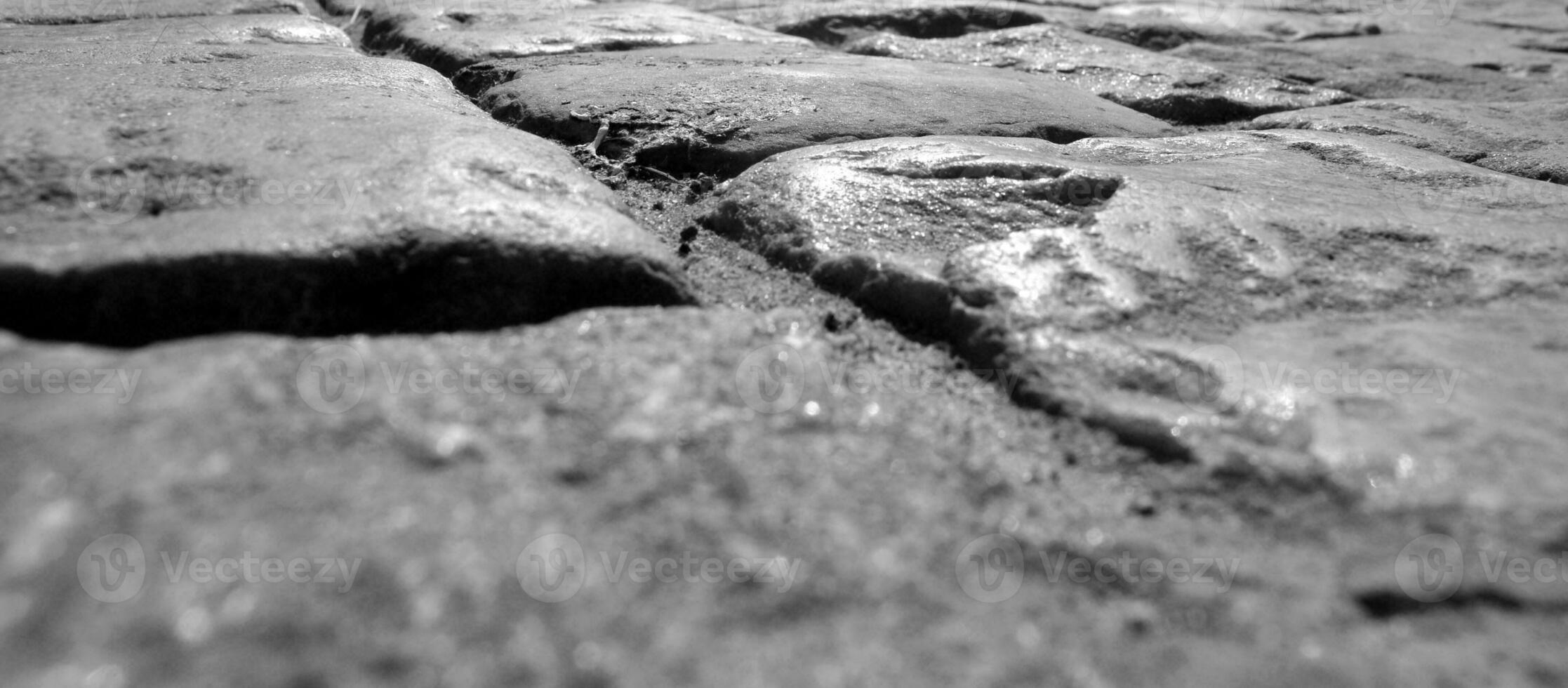 Road pavement made of stones, close view black and white background photo