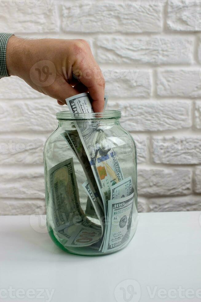 de los hombres mano tomando fuera papel dólar billete de banco desde vaso tarro foto