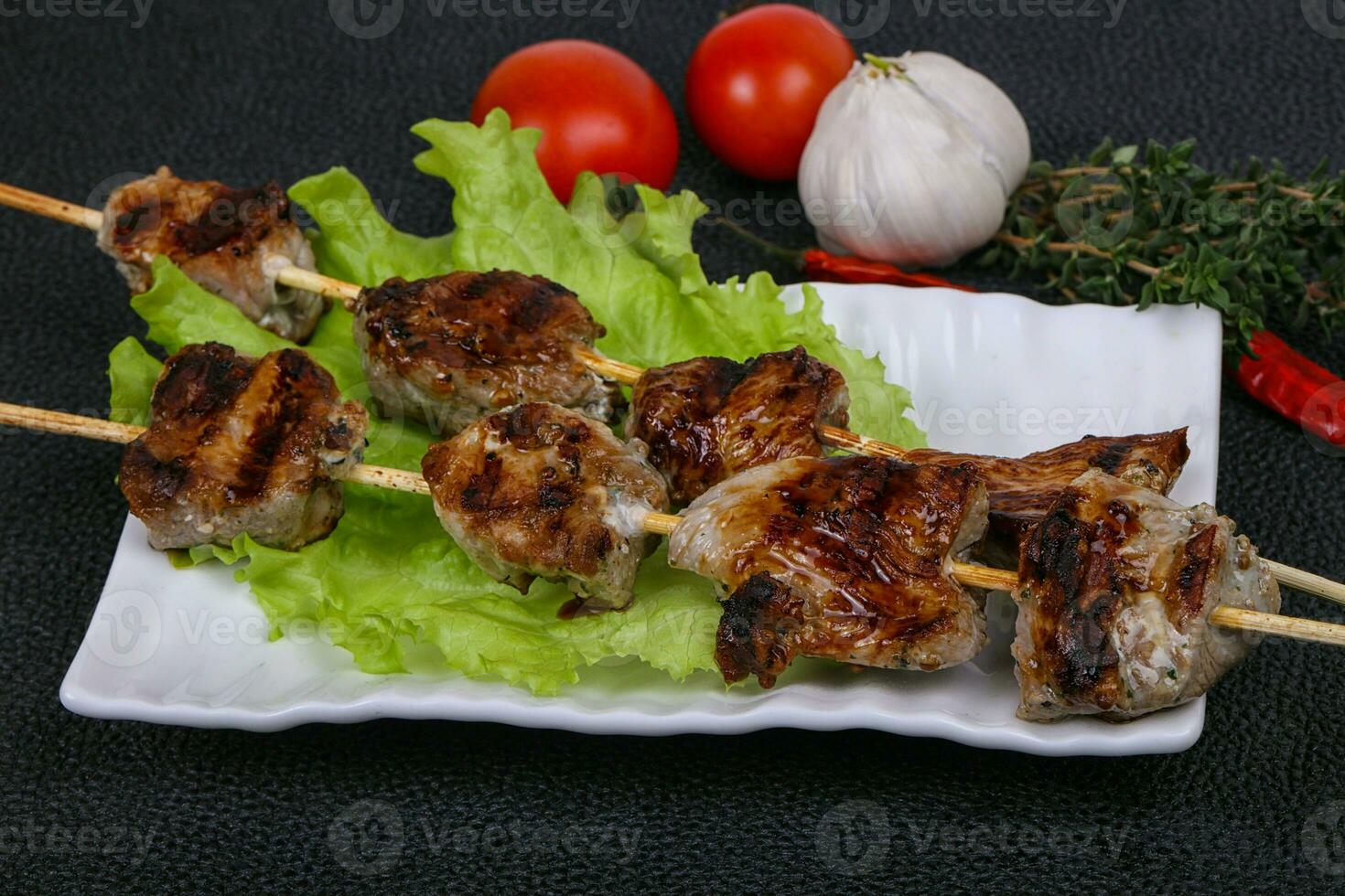 brochetas de kebab de cerdo en el plato con hojas de ensalada y tomates foto