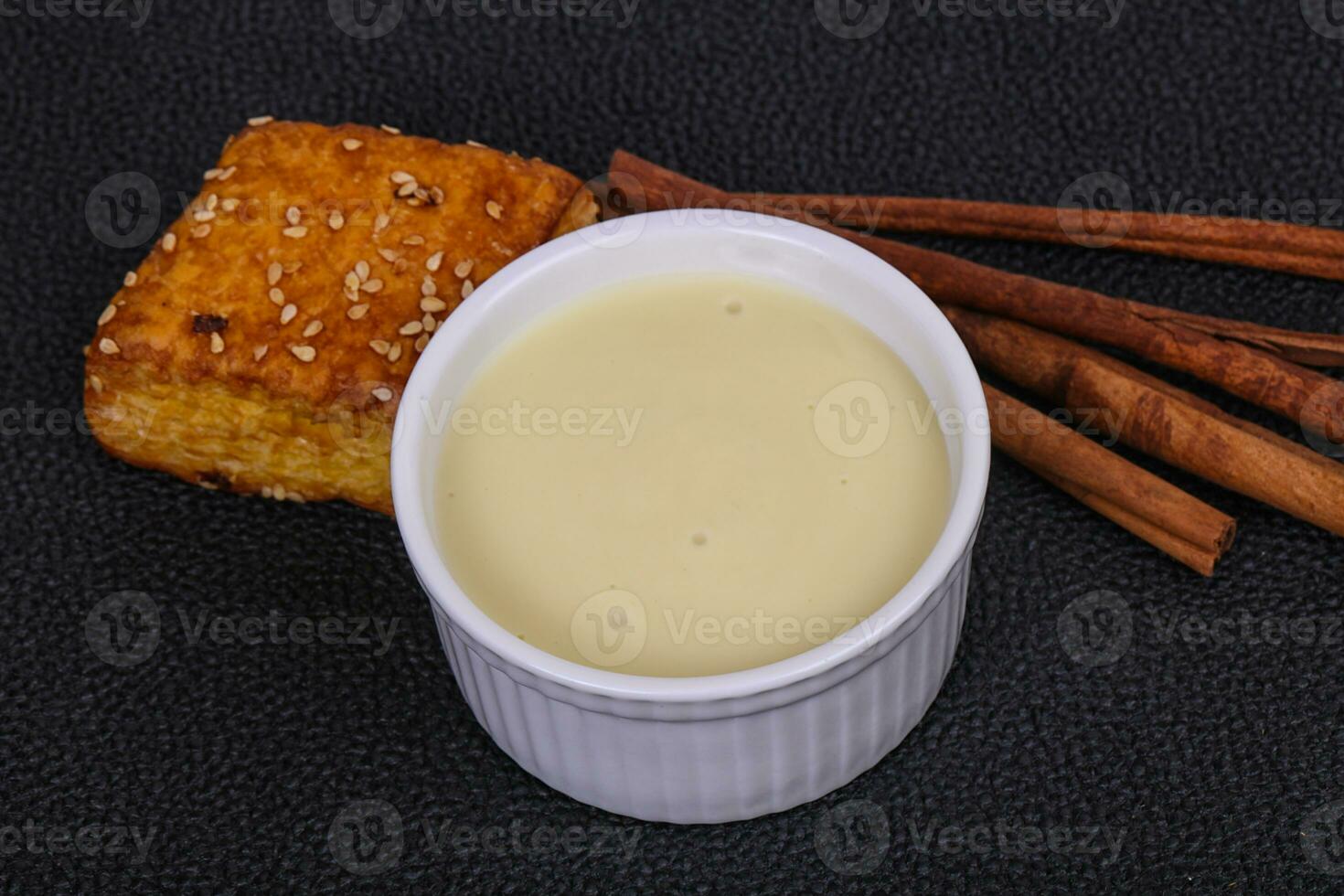 Condenced milk in the bowl with sinnamon and pastry photo
