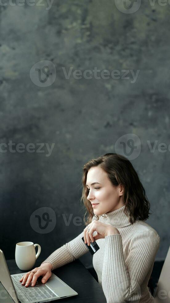 Young Woman Shopping Online. Holding Credit Card and Using Laptop for E-Commerce Transactions photo