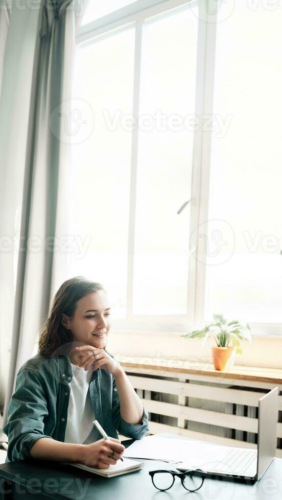 Young woman multitasking with laptop computer at office and student girl working remotely from home. Online work, study, freelance, and modern office lifestyle concept photo