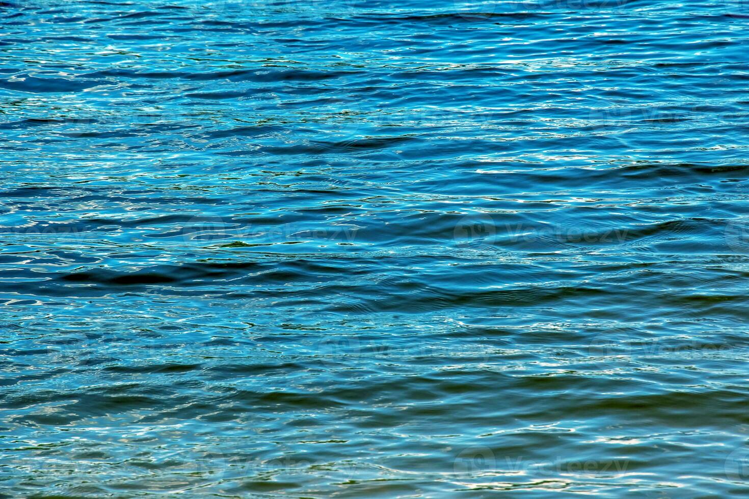 Fondo de textura de ondulación de agua. superficie de agua ondulada durante la puesta de sol, luz dorada reflejada en el agua. foto