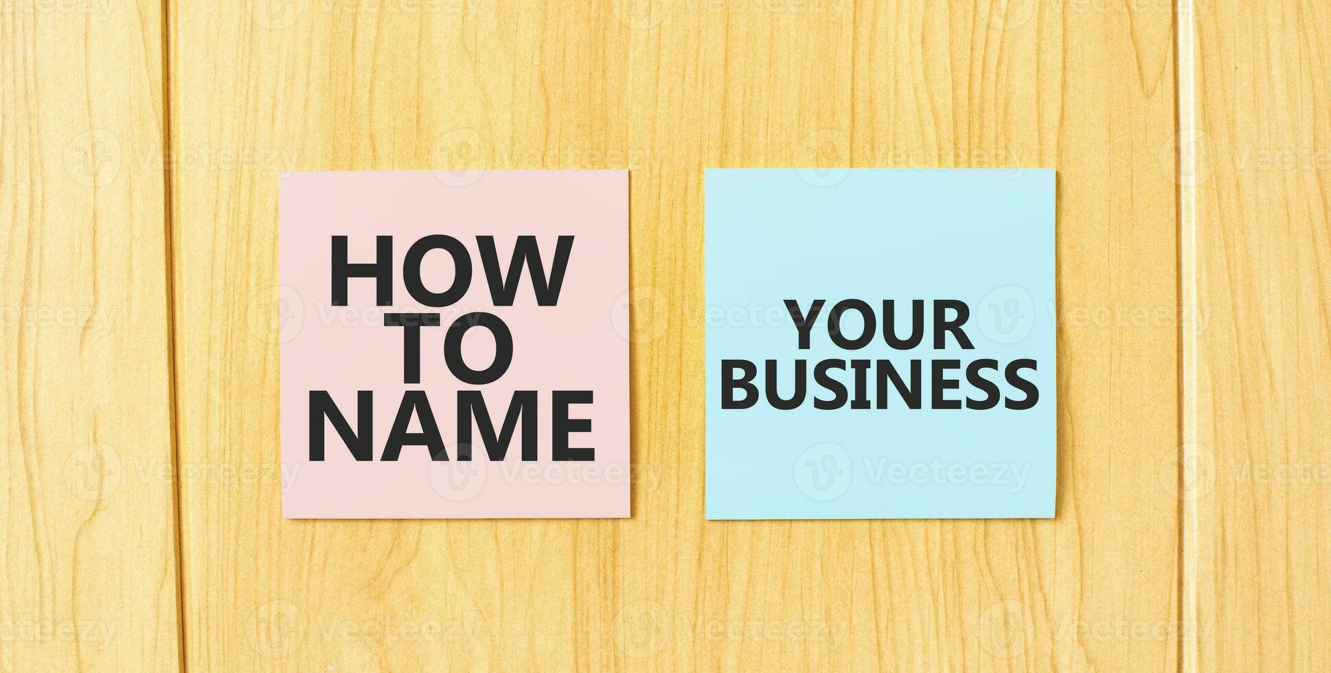 Inscription HOW TO NAME YOUR BUISINESS on pink and blue square sticky sticker on wooden wall photo