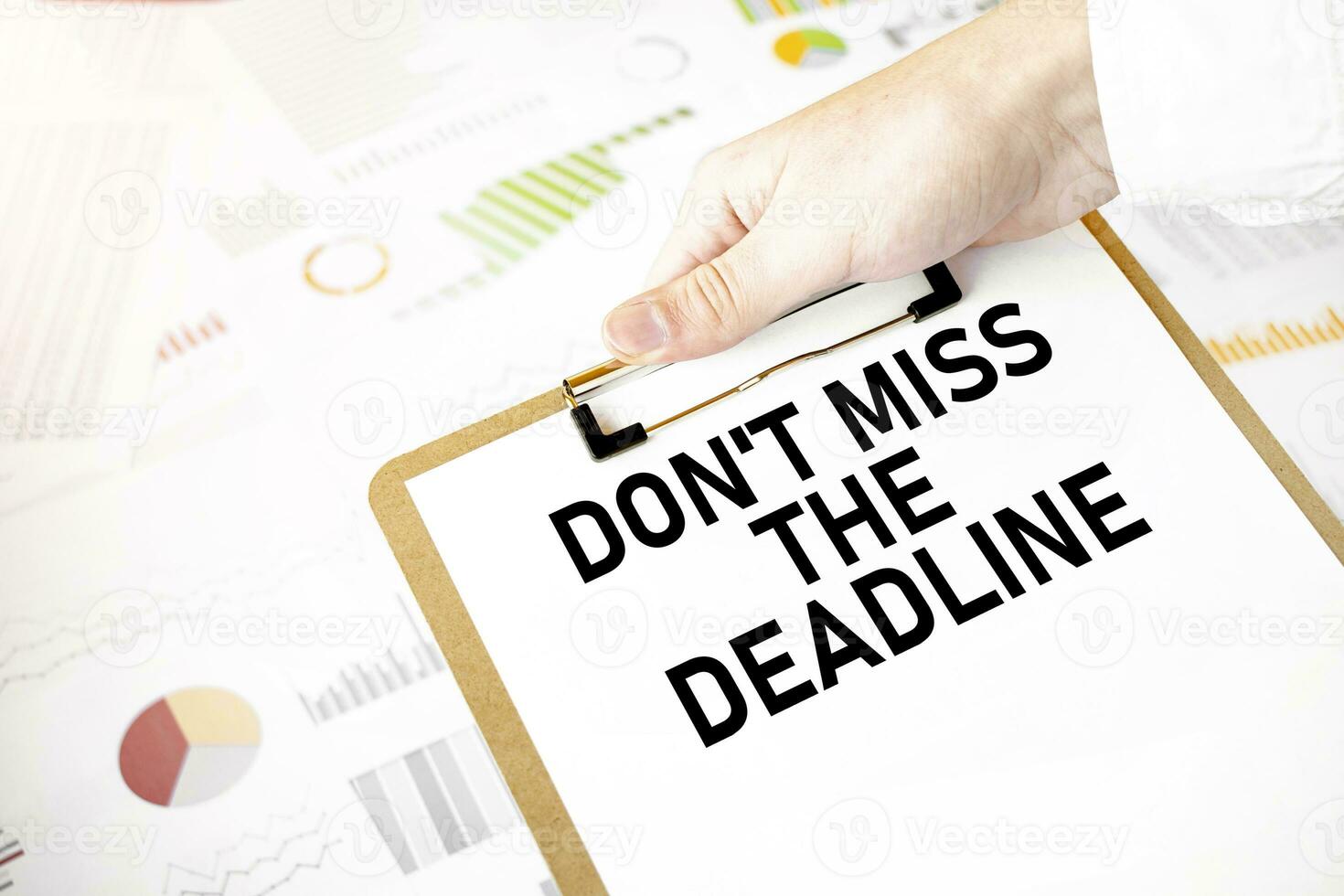 Text don't miss the deadline on white paper plate in businessman hands with financial diagram. Business concept photo