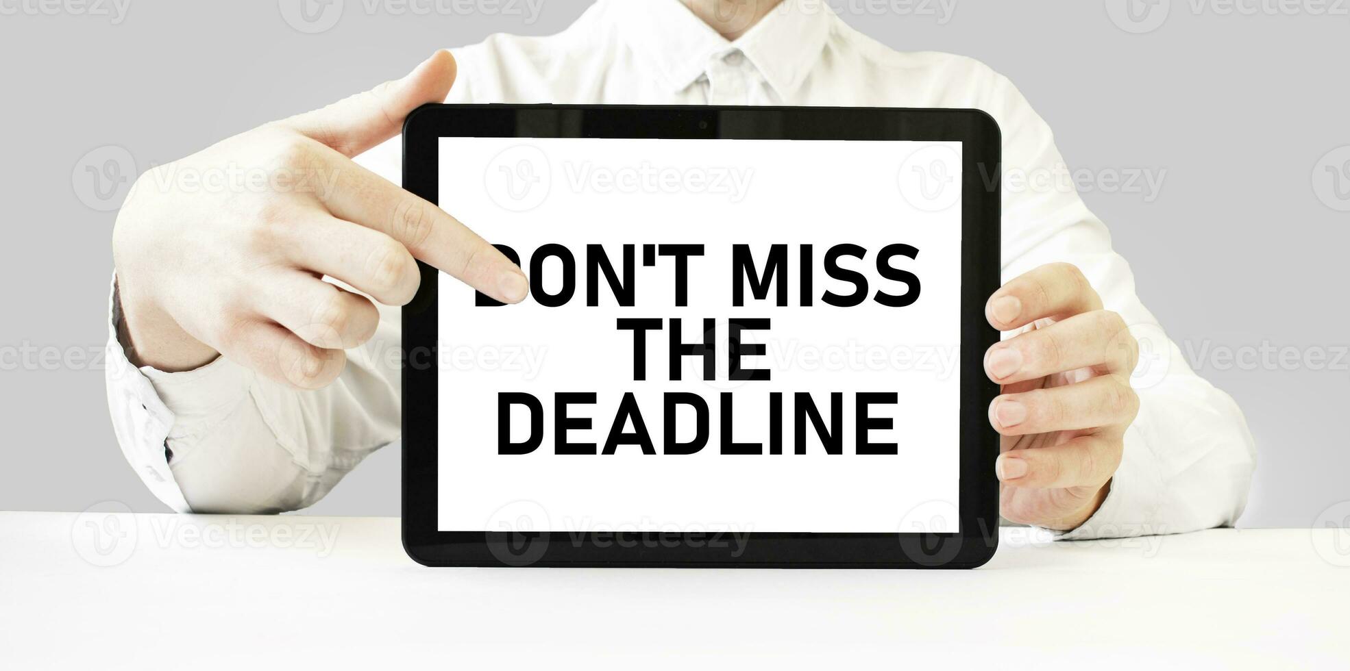 Text don't miss the deadline on tablet display in businessman hands on the white background. Business concept photo