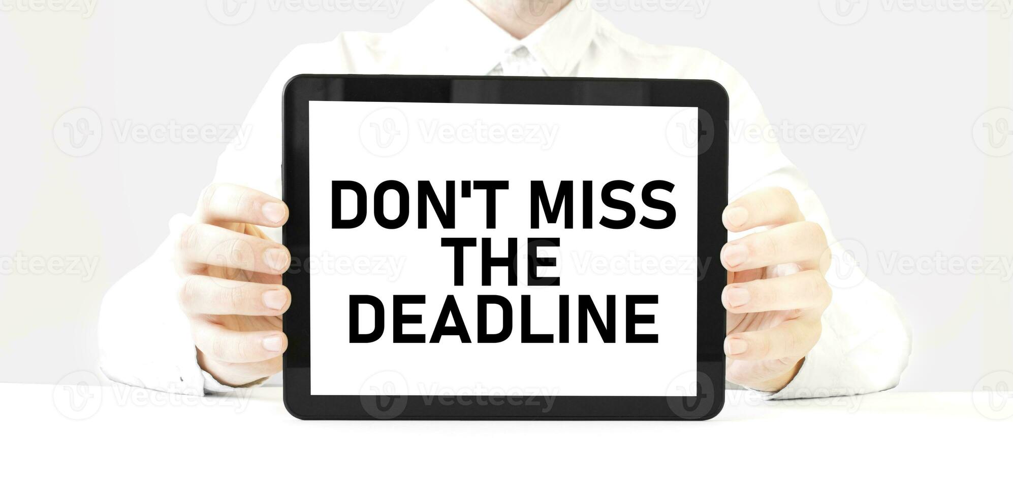 Text don't miss the deadline on tablet display in businessman hands on the white background. Business concept photo