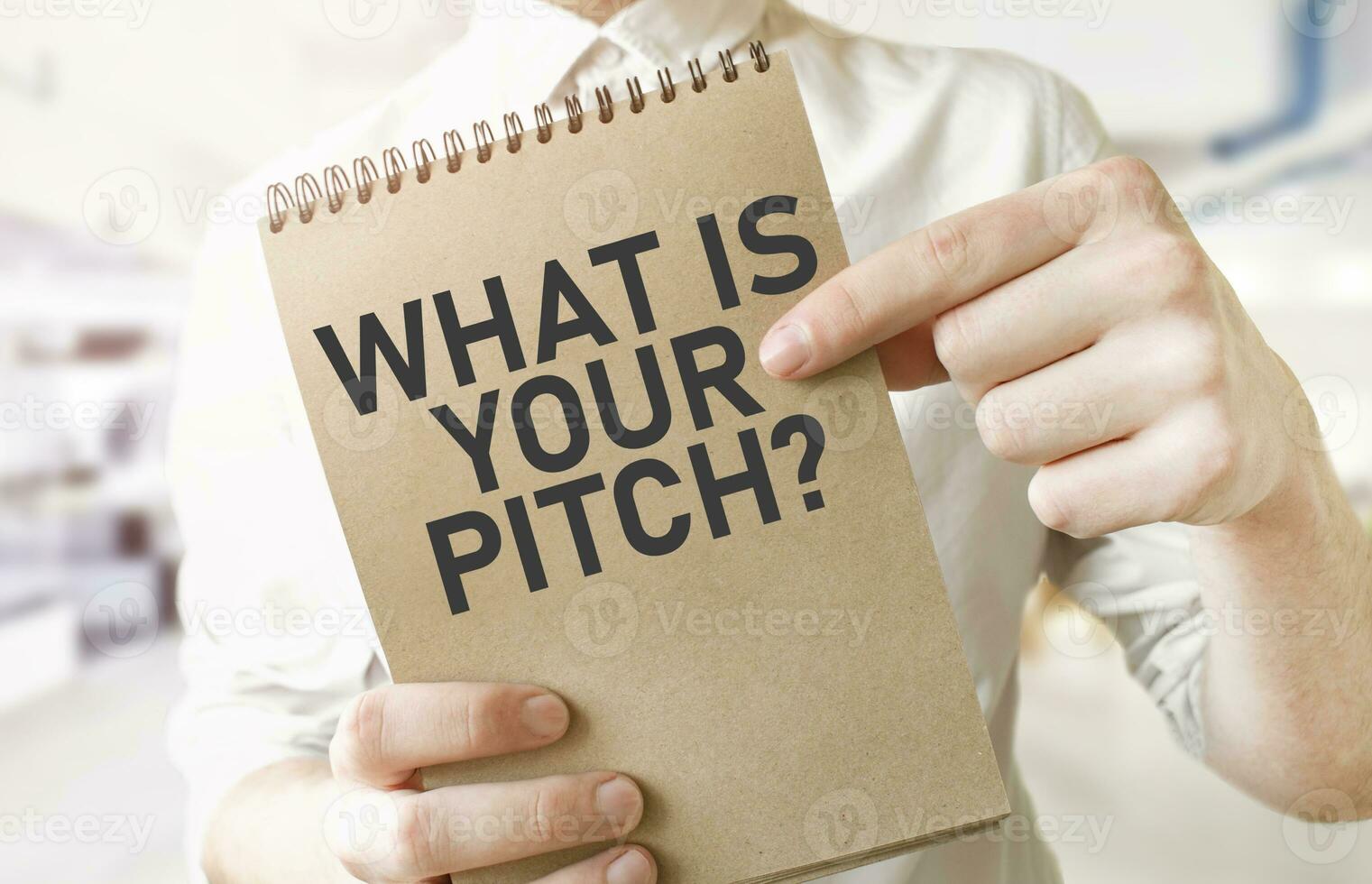 Text WHAT IS YOUR PITCH on brown paper notepad in businessman hands in office. Business concept photo