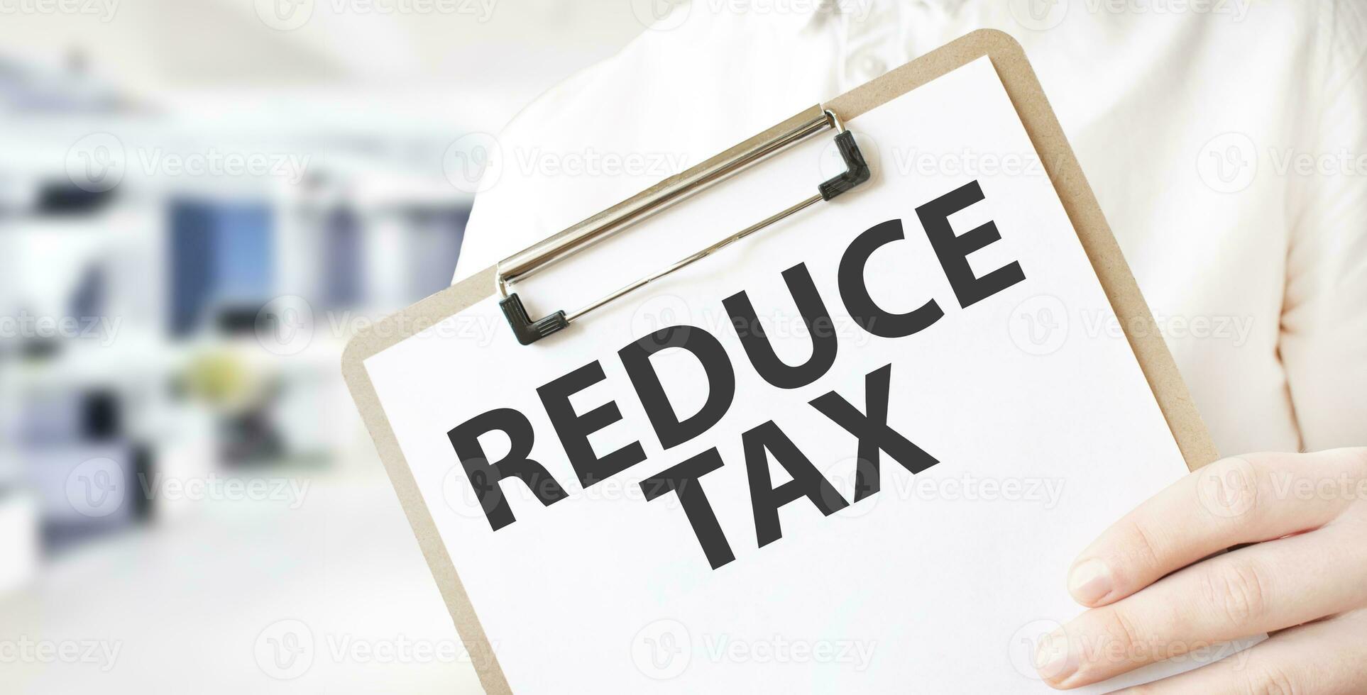 Text REDUCE TAX on white paper plate in businessman hands in office. Business concept photo