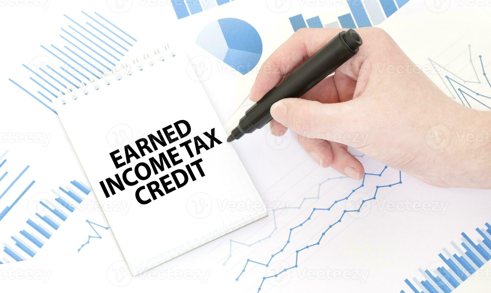 Businessman holding a black marker, notepad with text EARNED INCOME TAX CREDIT, business concept photo