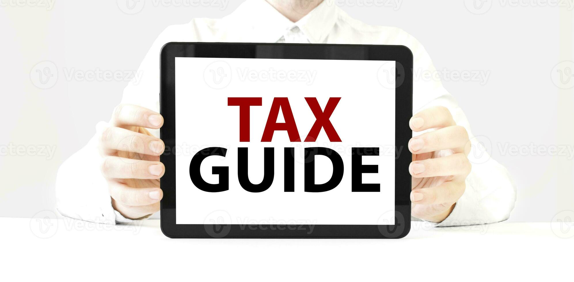 Text TAX GUIDE on tablet display in businessman hands on the white background. Business concept photo
