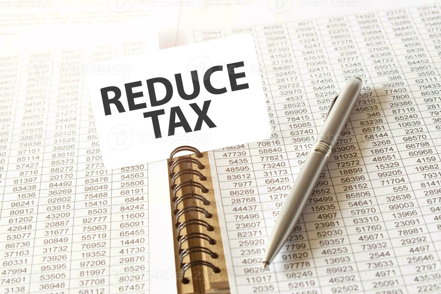 Text REDUCE TAX on paper card,pen, financial documentation on table photo