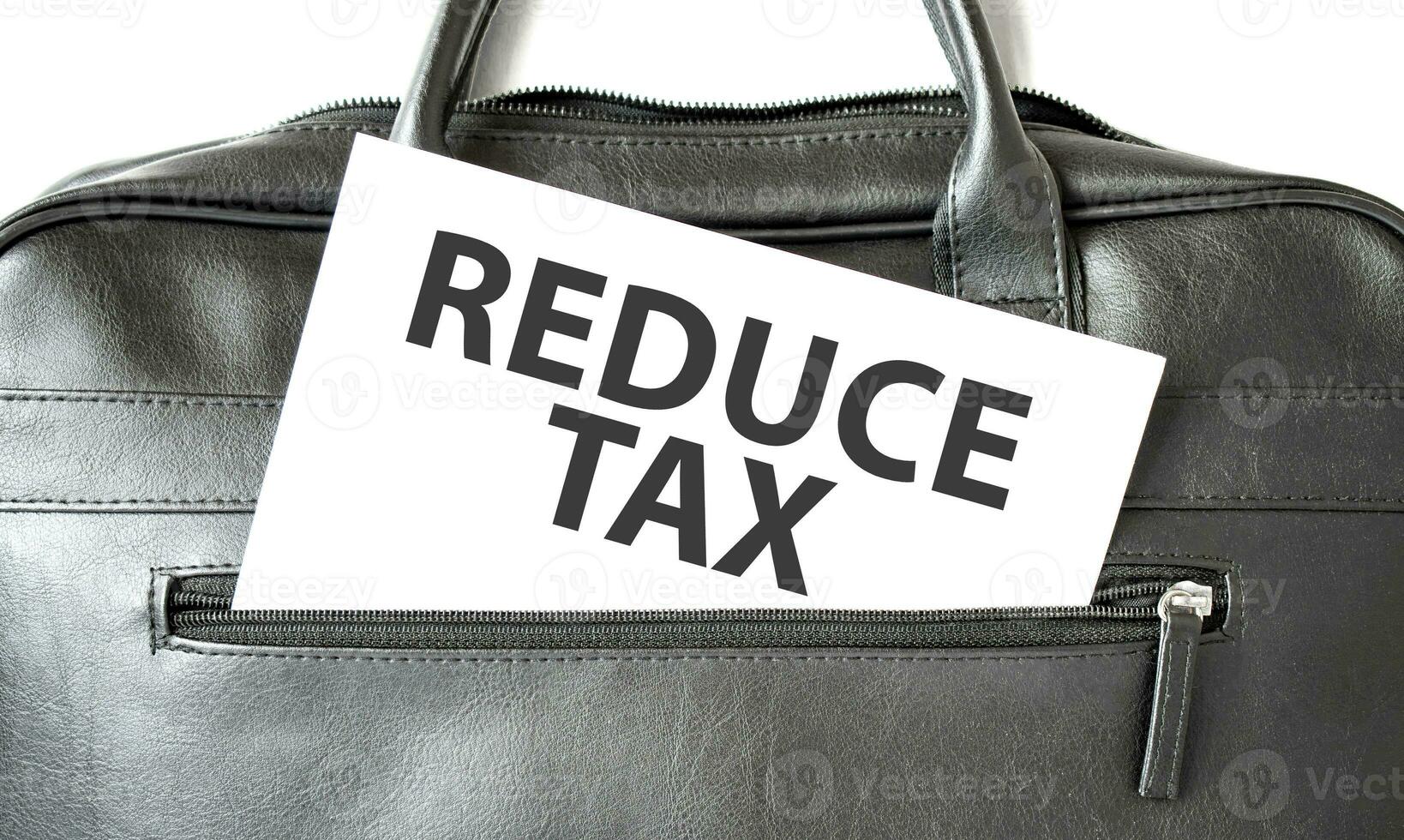 Text REDUCE TAX writing on white paper sheet in the black business bag. Business concept photo