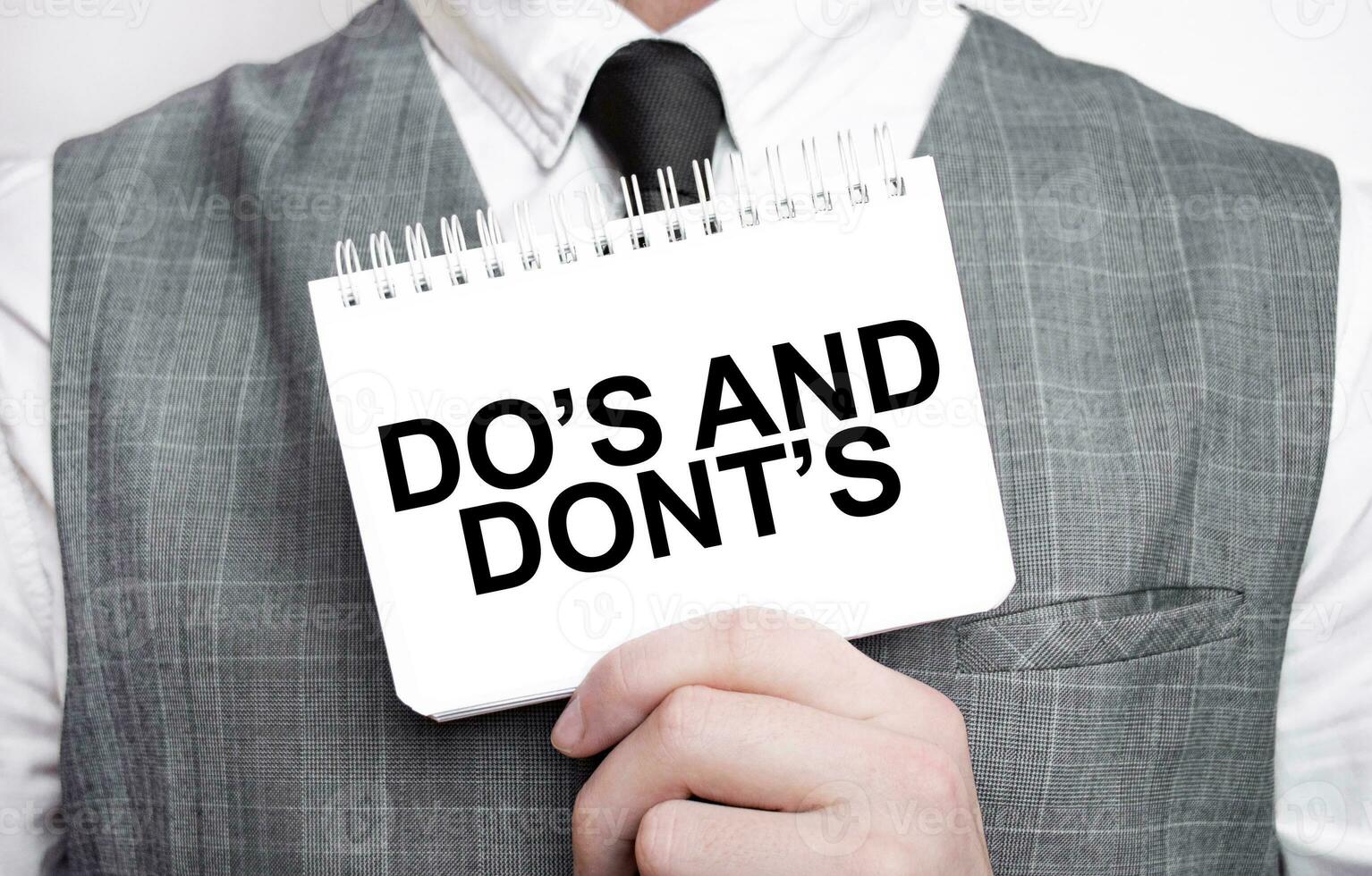 Businessman with notebook with text DO's and DONT's photo