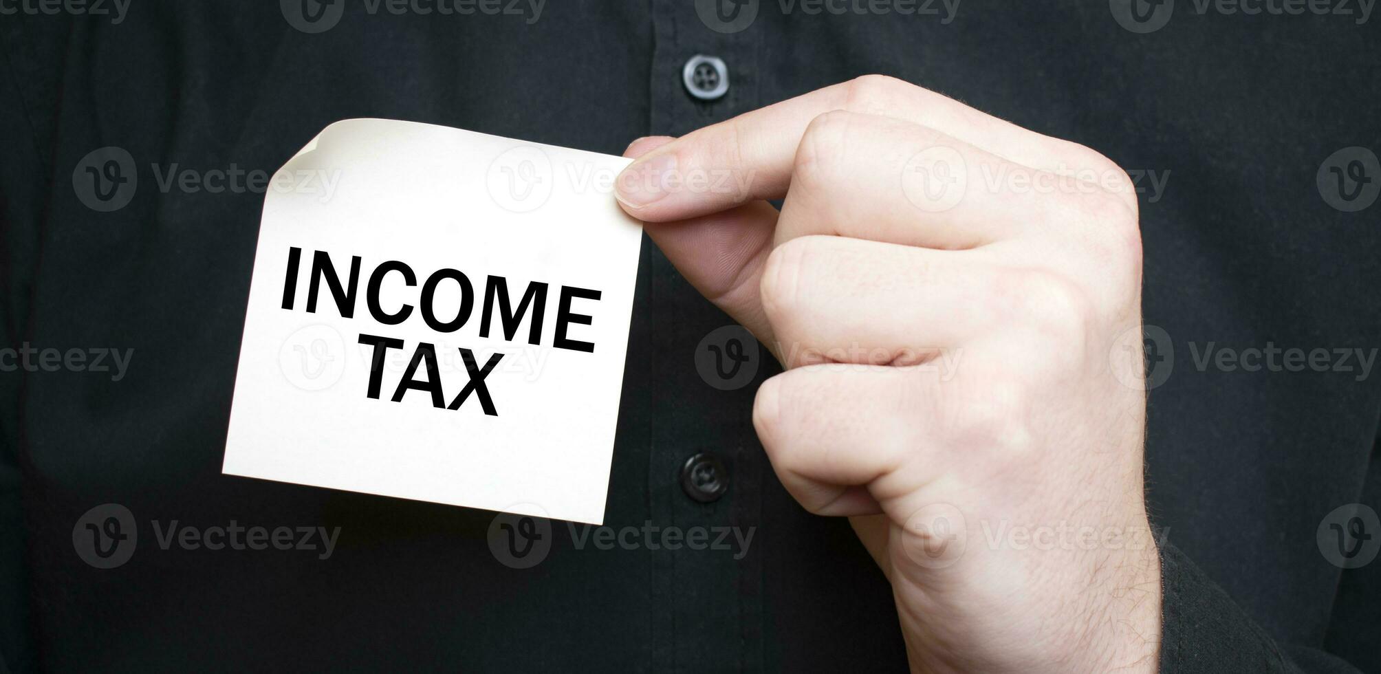 Businessman holding a card with text INCOME TAX, business concept photo