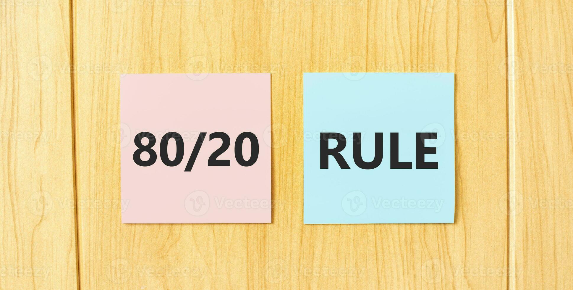 Inscription 80 and 20 rule on pink and blue square sticky sticker on wooden wall photo