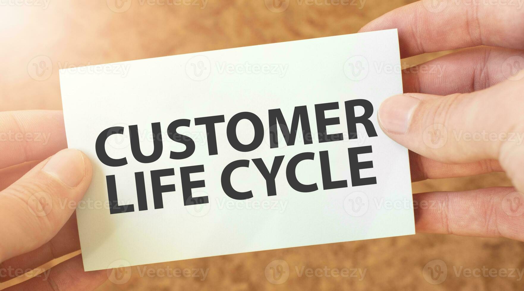 CUSTOMER LIFE CYCLE word inscription on white card paper sheet in hands of a businessman. recap concept. red and white paper photo