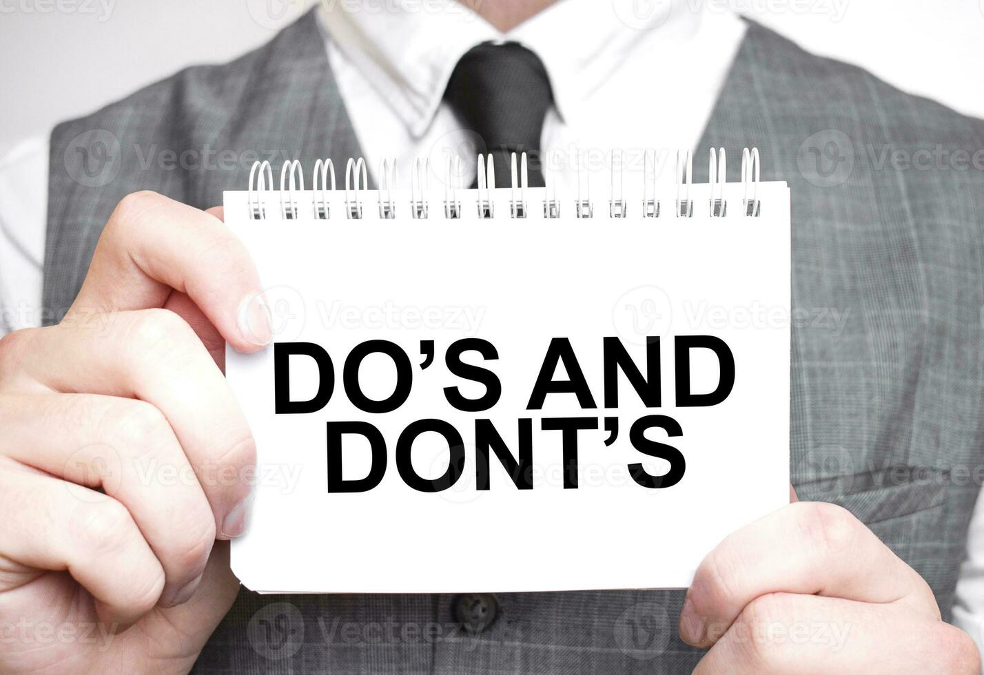 Businessman with notebook with text DO's and DONT's photo