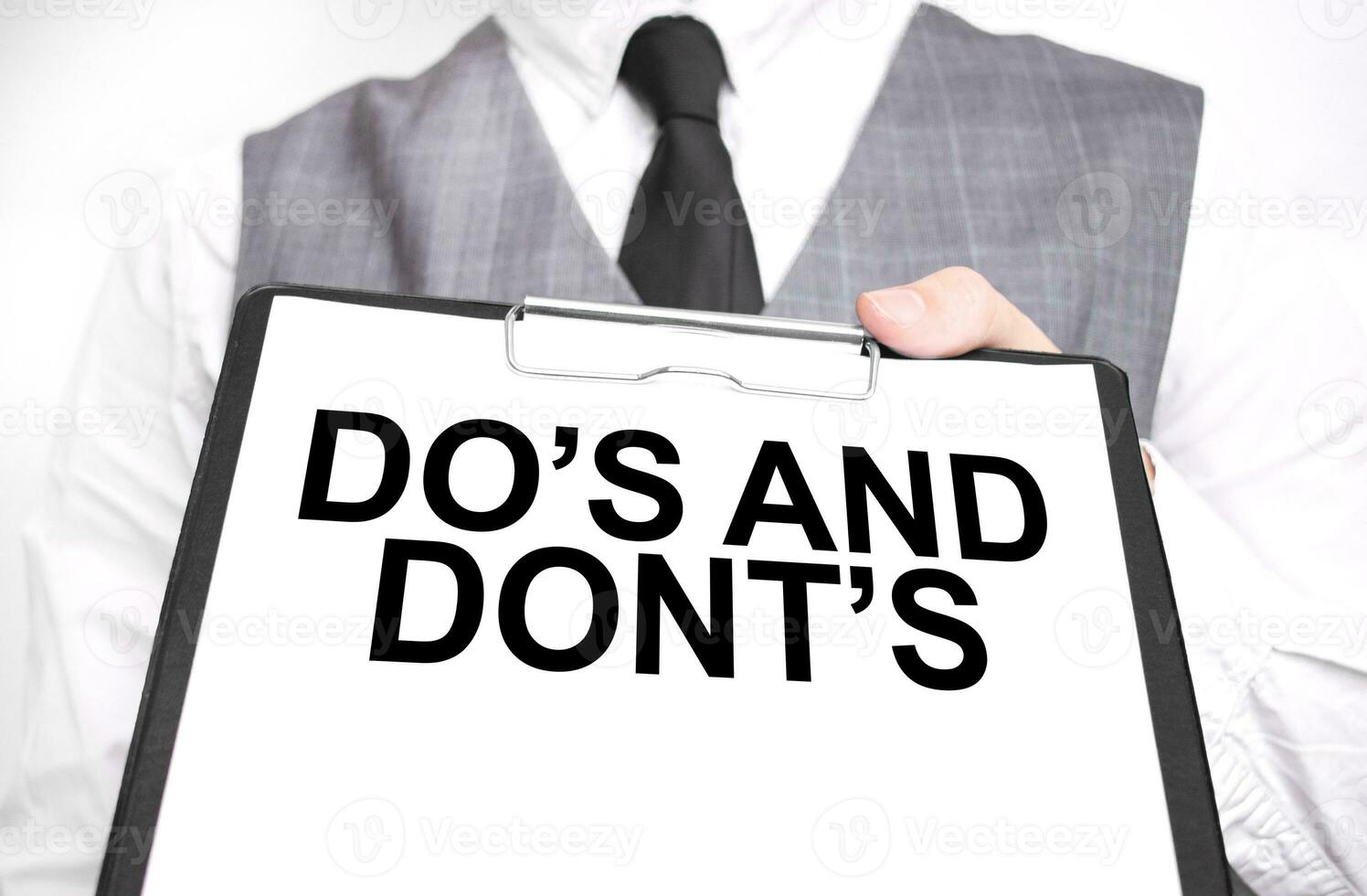Businessman holding sheet of paper with a message DO's and DONT's photo