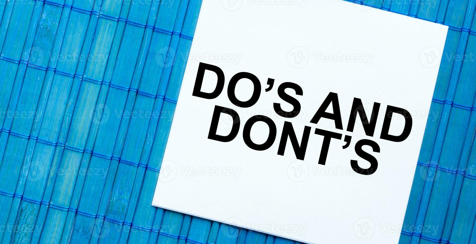 blank note pad with DO's and DONT's text on blue wooden background photo