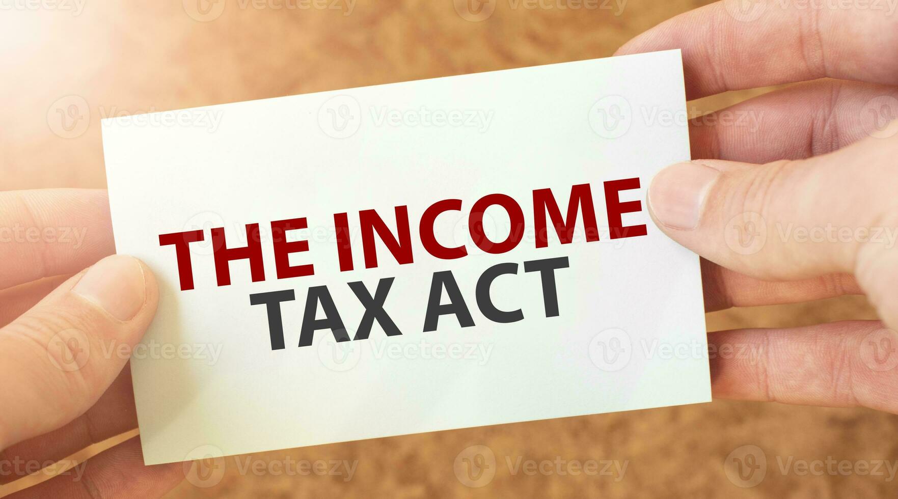 THE INCOME TAX ACT word inscription on white card paper sheet in hands of a businessman. recap concept. red and white paper photo