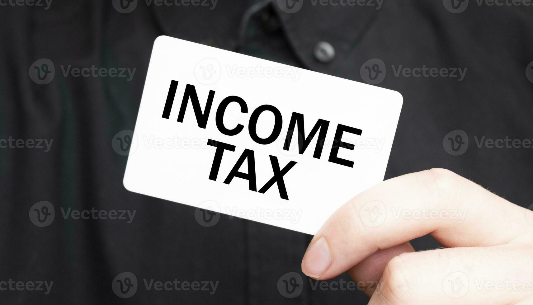 Businessman holding a card with text INCOME TAX, business concept photo