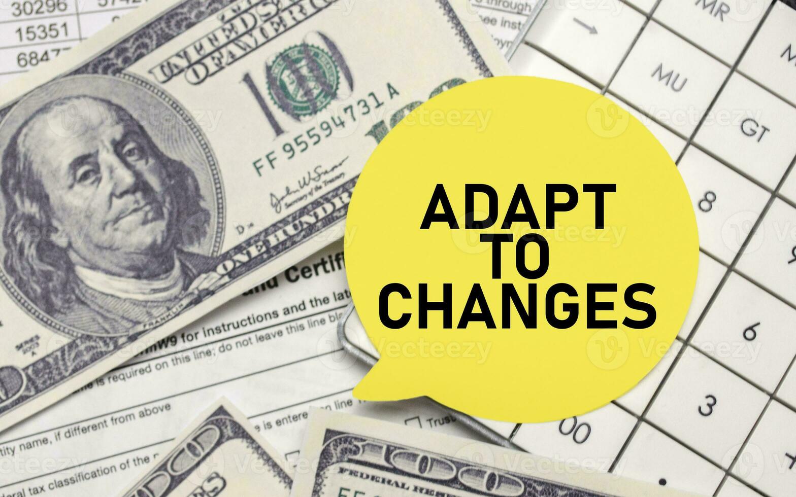 ADAPT TO CHANGES on yellow sticker with dollars and calculator photo