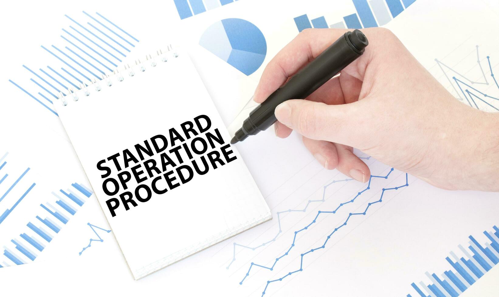 Businessman holding a black marker, notepad with text STANDARD OPERATION PROCEDURE ,business concept photo