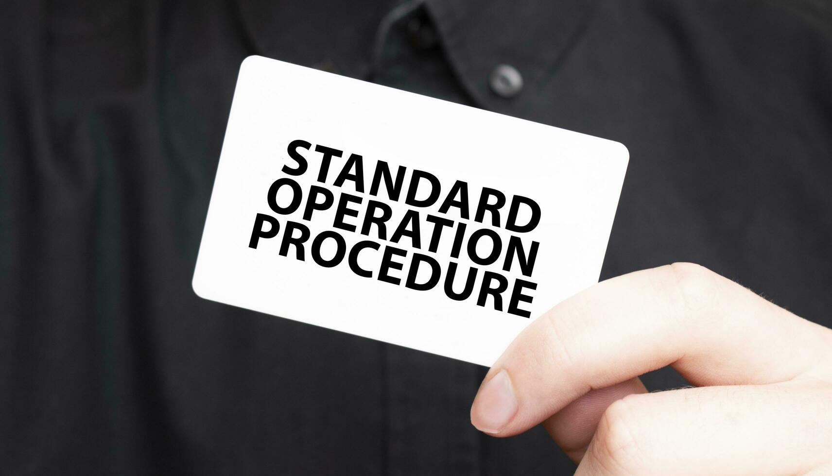 Businessman holding a card with text STANDARD OPERATION PROCEDURE, business concept photo