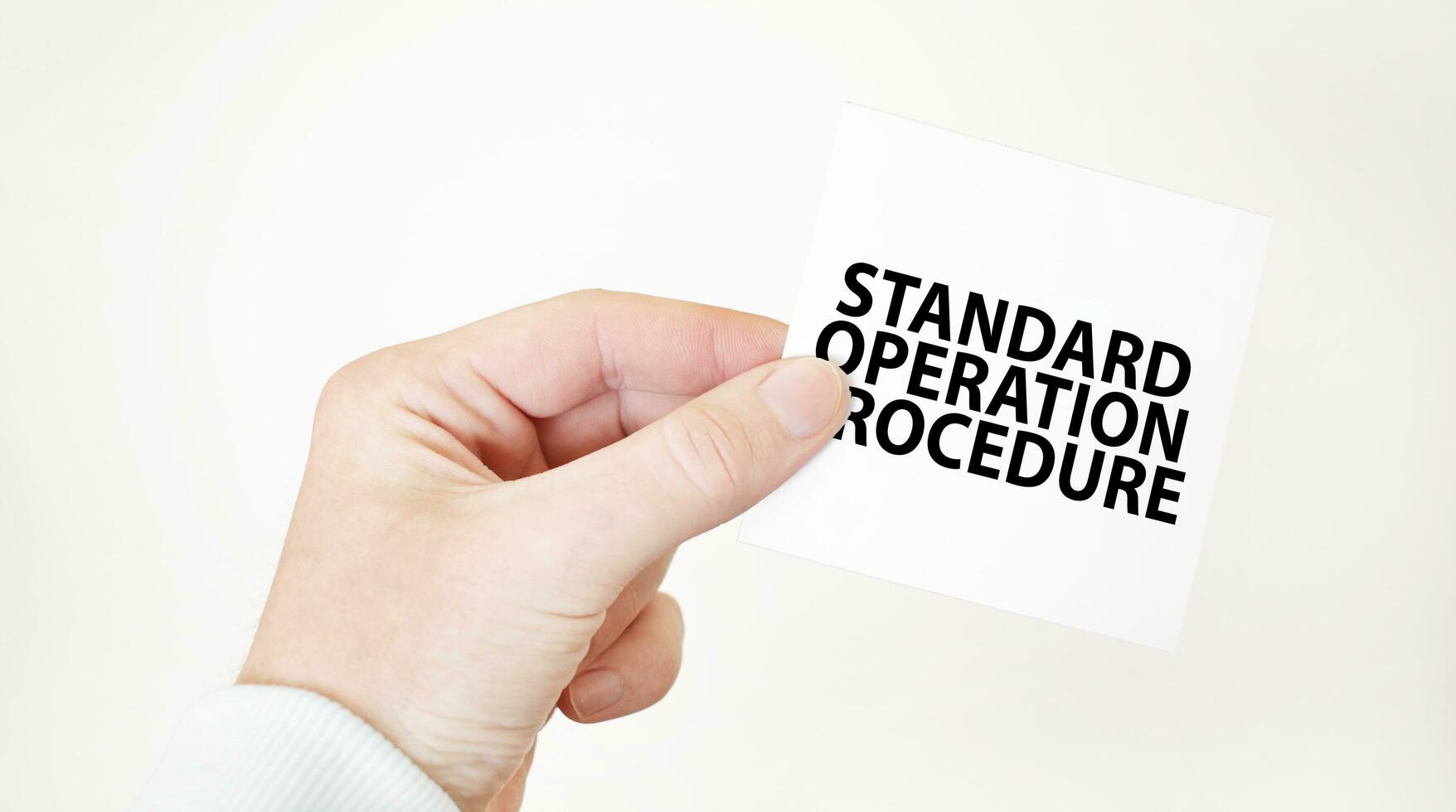 Businessman holding a card with text STANDARD OPERATION PROCEDURE, business concept photo