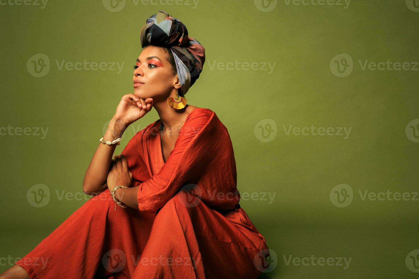 Stylish woman with  colorful turban in studio. Beautiful female model with vibrant makeup against  green background. photo