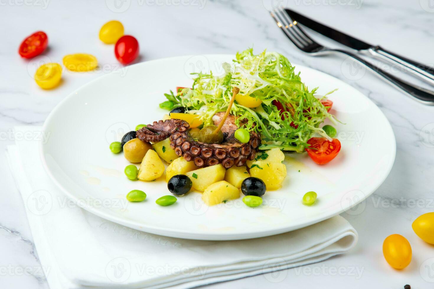 salad with olives, herbs, cherry tomatoes, potatoes and octopus tentacles side view photo