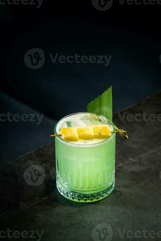 lime coctail with pineapple pieces and cinnamon side view photo