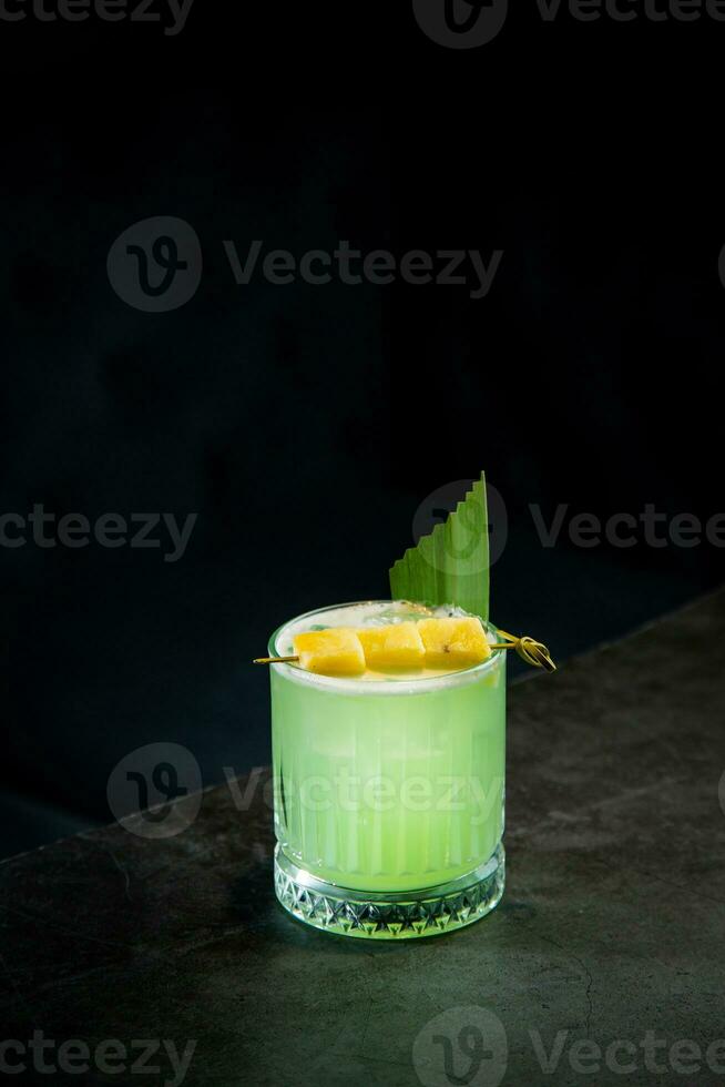 lime coctail with pineapple pieces and cinnamon side view photo