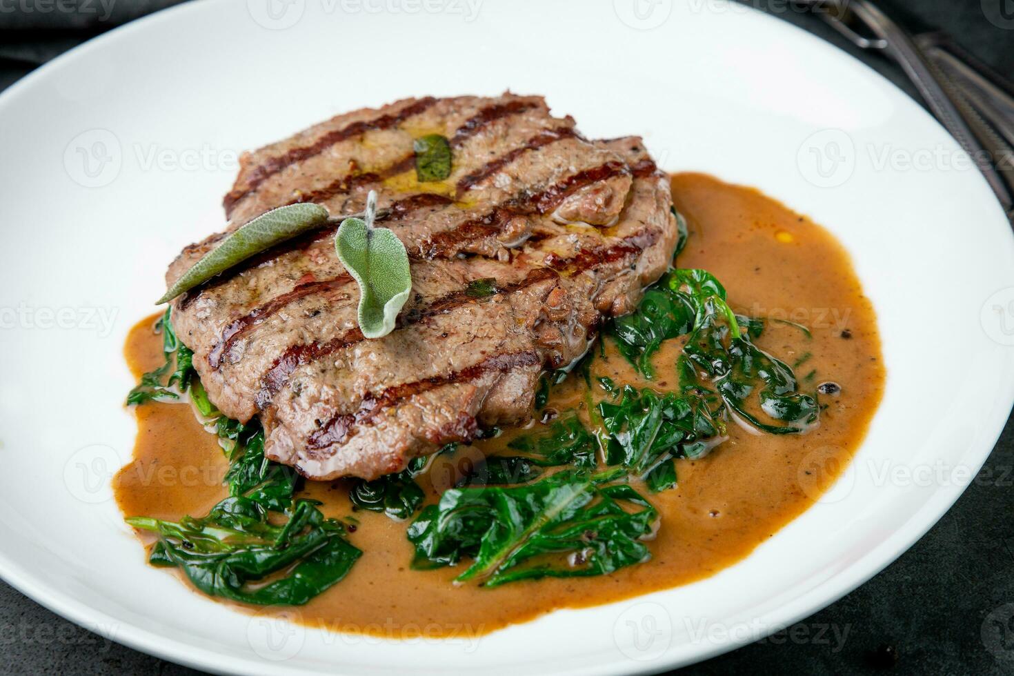 beef steak with gravy and herbs on a white plate photo