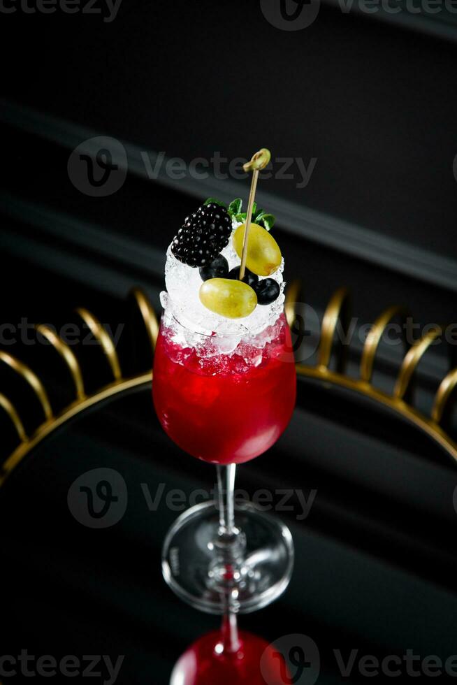red cocktail on a dark background with whipped cream topping side view photo