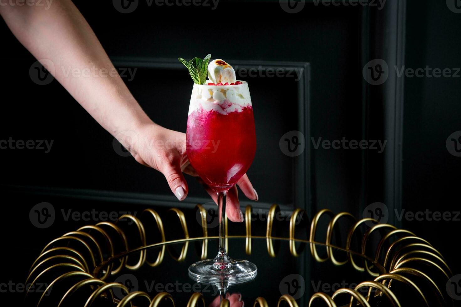 red cocktail on a dark background with whipped cream topping photo