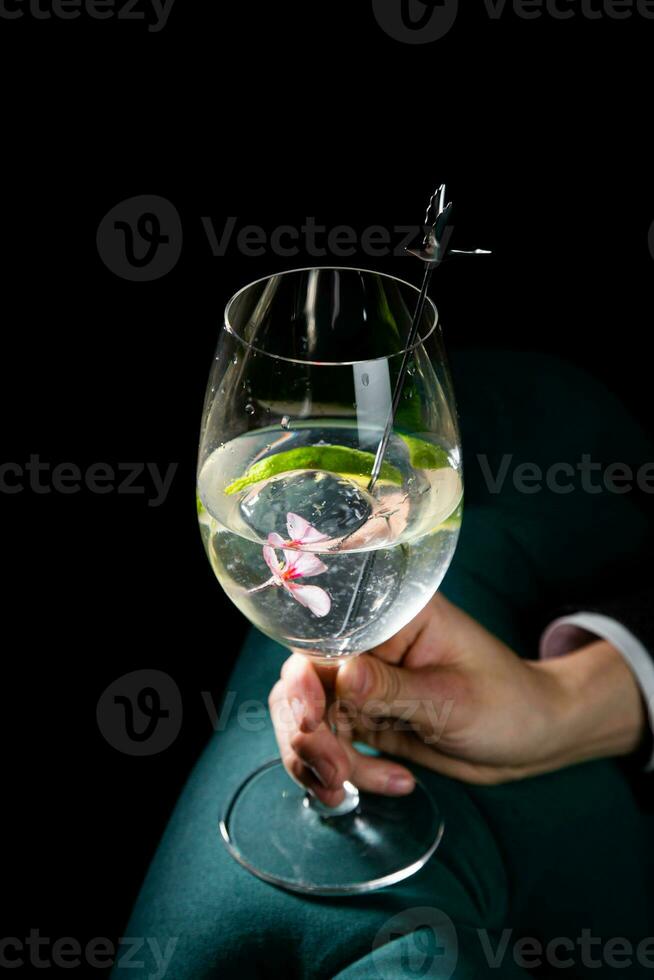 transparent cocktail with lime in a wine glass on a dark background side view photo