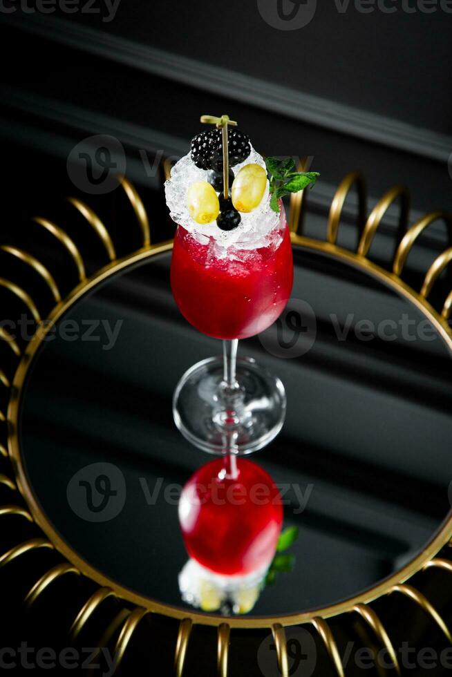 red cocktail on a dark background with whipped cream topping side view photo