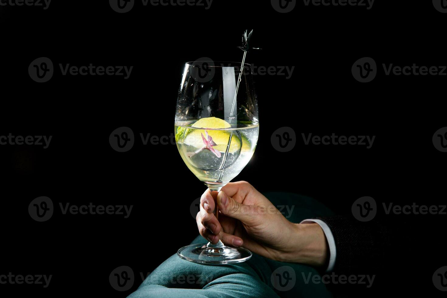 transparent cocktail with lime in a wine glass on a dark background side view photo