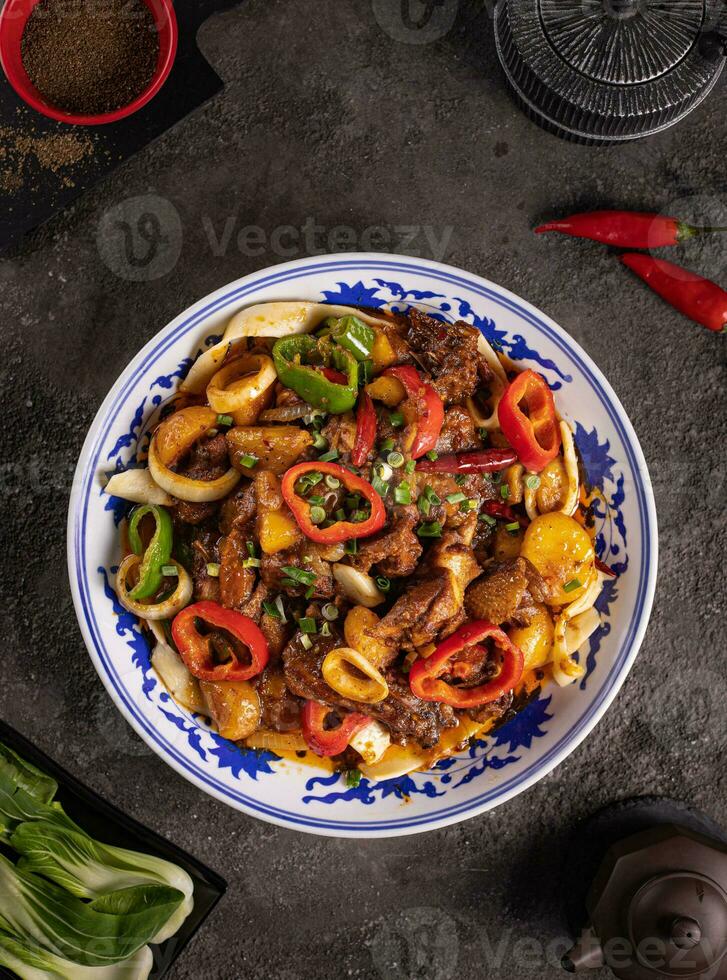 noodles with bell pepper, potatoes, meat and herbs in a plate with a pattern top view photo