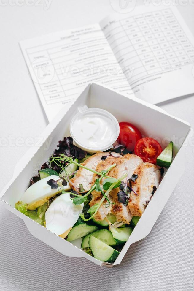 pieces of chicken with vegetables, herbs and sauce in a lunchbox photo