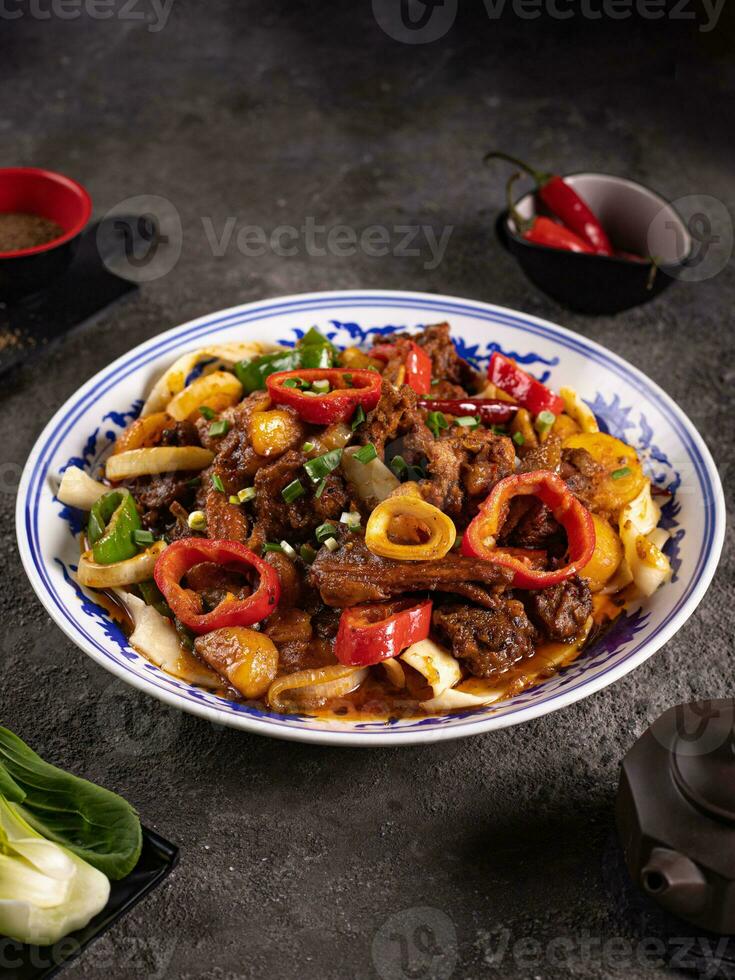 noodles with bell pepper, potatoes, meat and herbs in a plate with a pattern side view photo