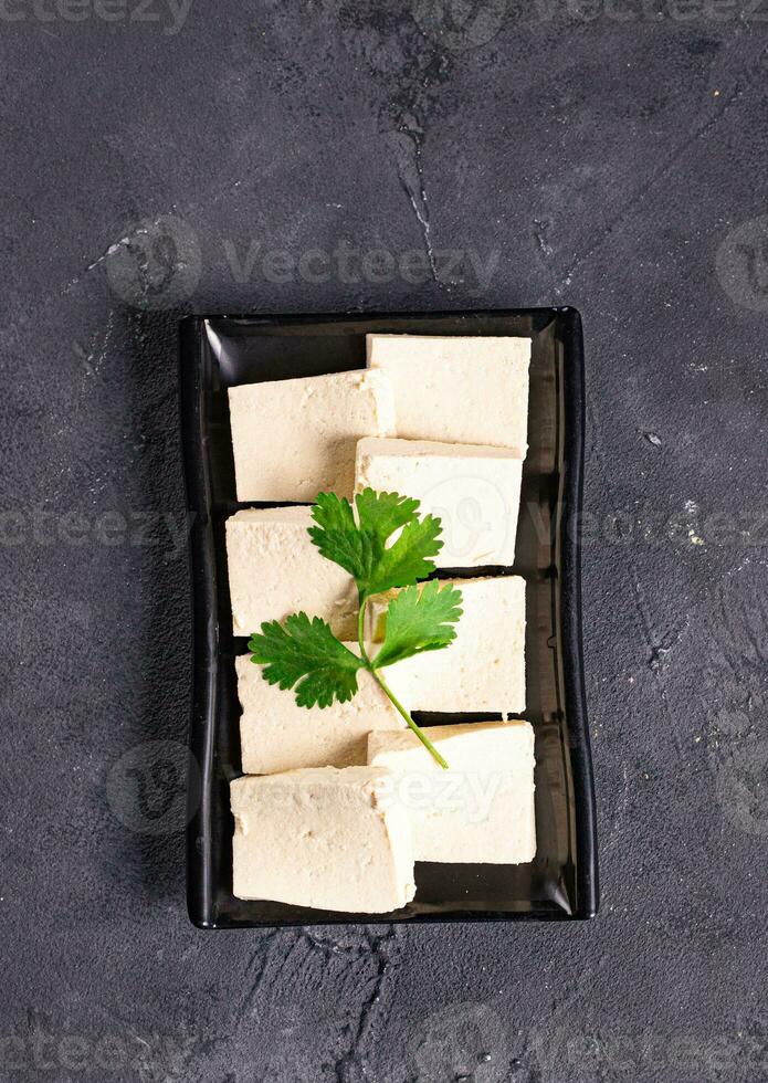 tofu slices with parsley on it on a black plate photo