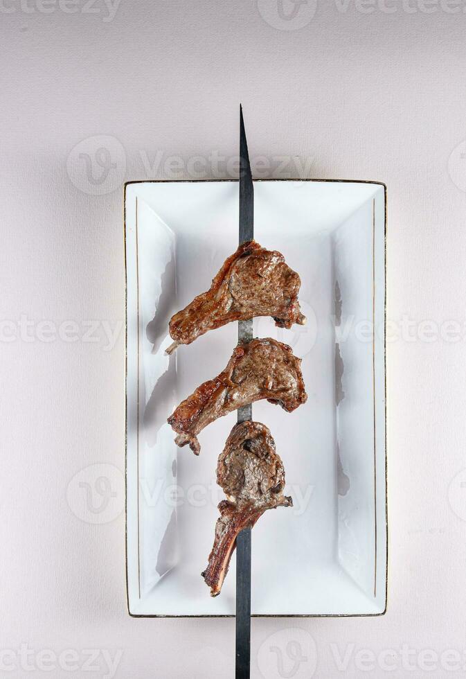 amazing lamb ribs on a skewer on a white plate. . View from above. Chinese cuisine photo