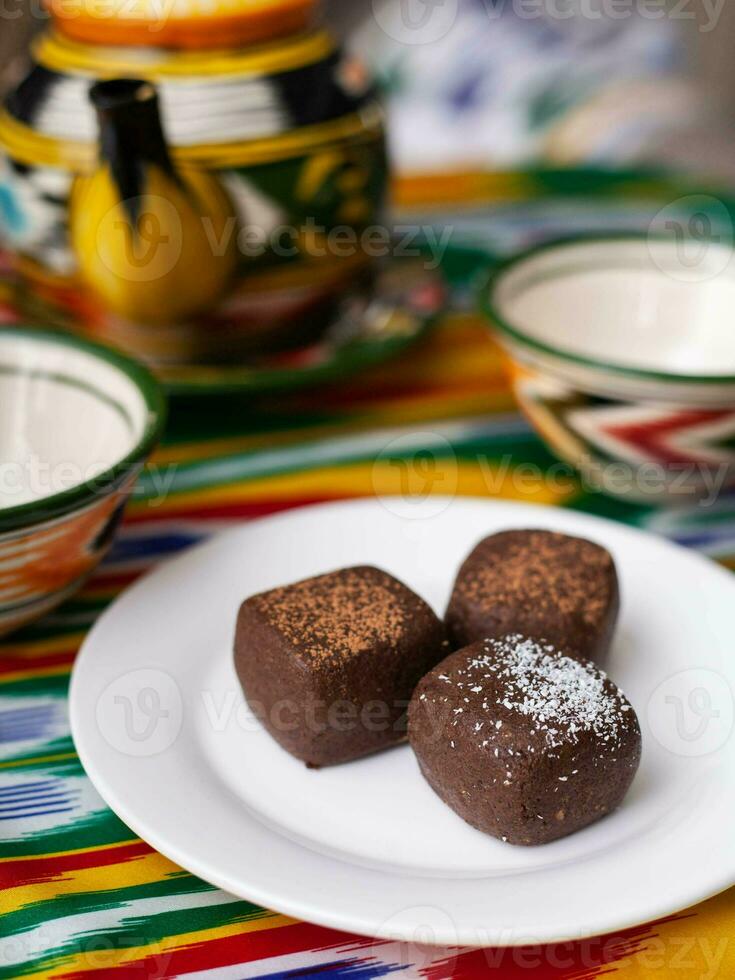 dessert chocolate brownie potatoes in oriental style on a tar with a teapot and a cup for tea. photo