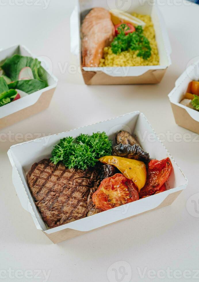 food in containers. proper nutrition, daily diet, weight loss. drink, veal steak with grilled vegetables, salmon steak with couscous side dish. Top view photo