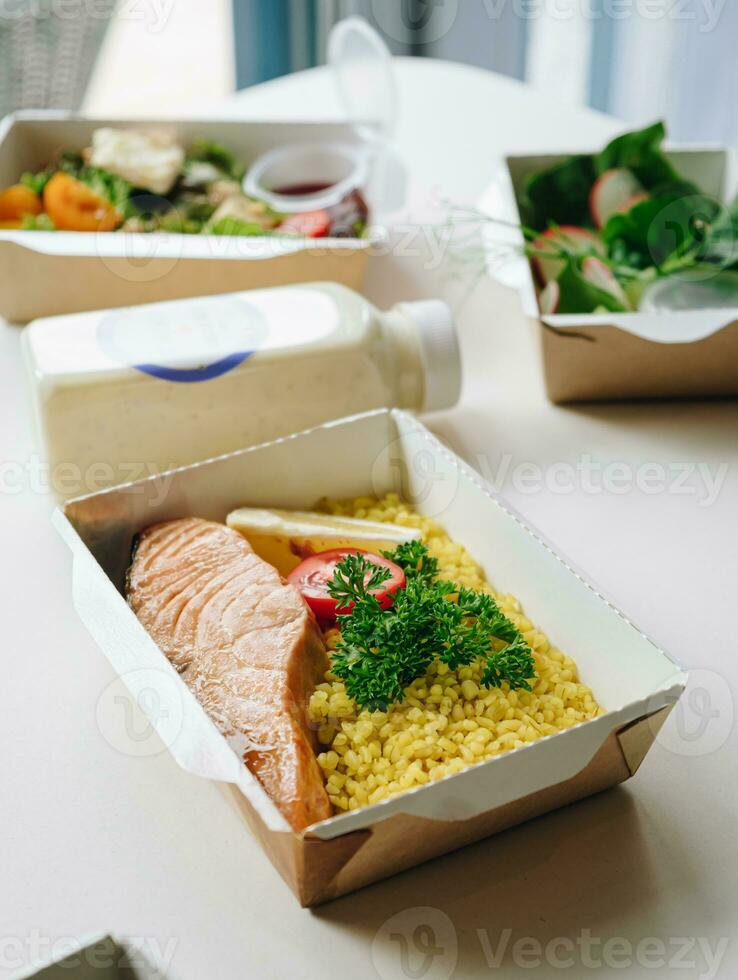 food in containers. proper nutrition, daily diet, weight loss. greens, tomato, lemon salmon steak with couscous side dish. Top view photo