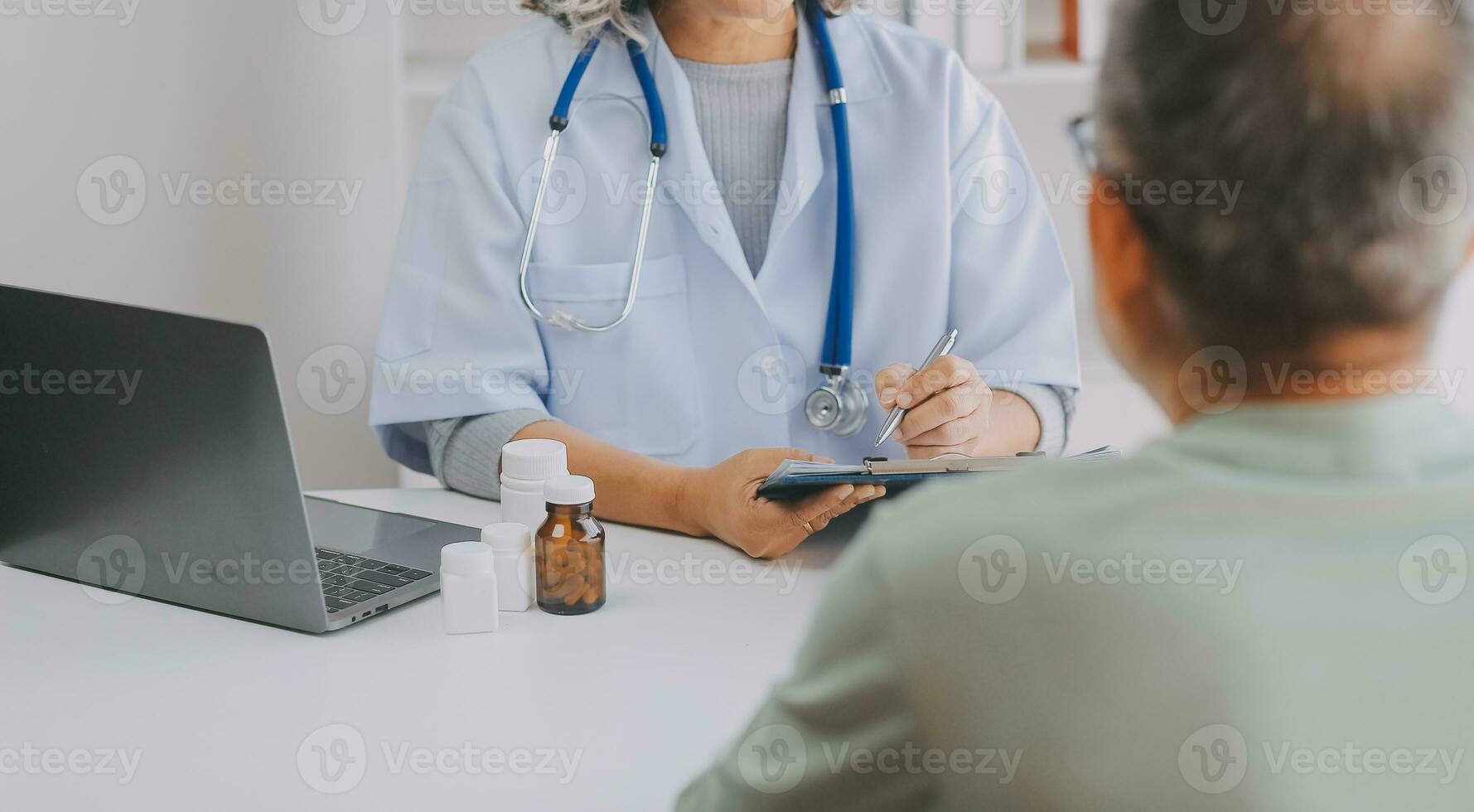 Mature Asian male doctor talking with his patient, explaining the procedure to old lady. photo