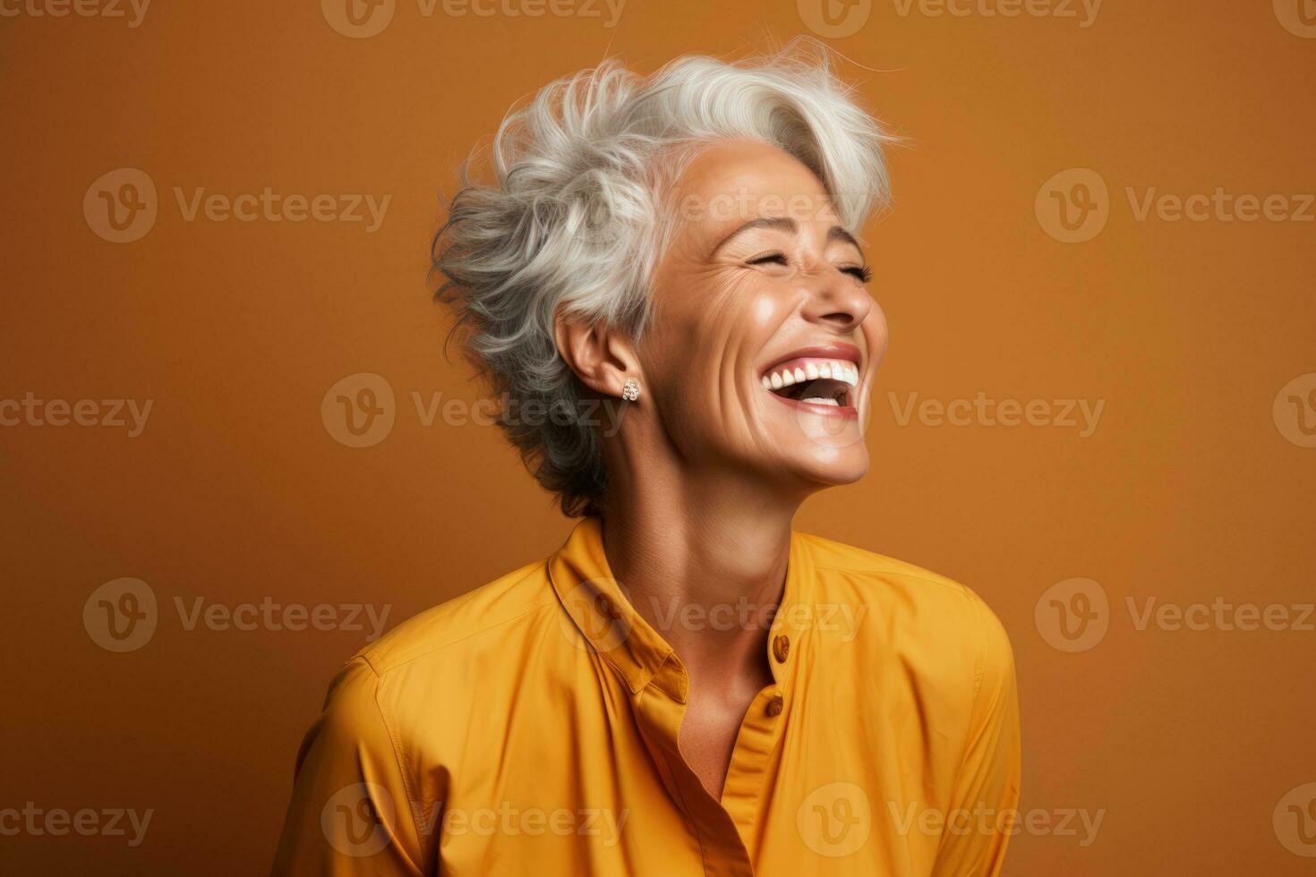 Senior woman laughing heartily isolated on a burnt sienna gradient background photo